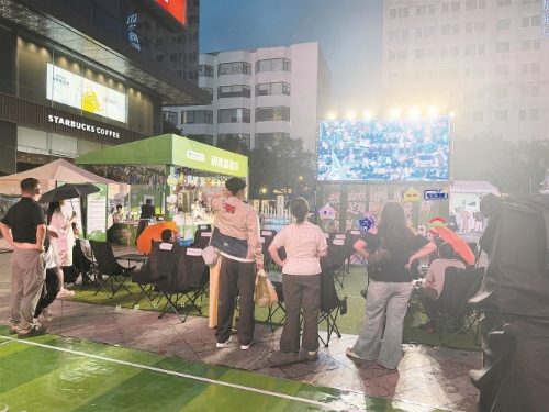在金鹰购物广场,市民冒雨观看滇超联赛实时转播。 记者孙潇摄